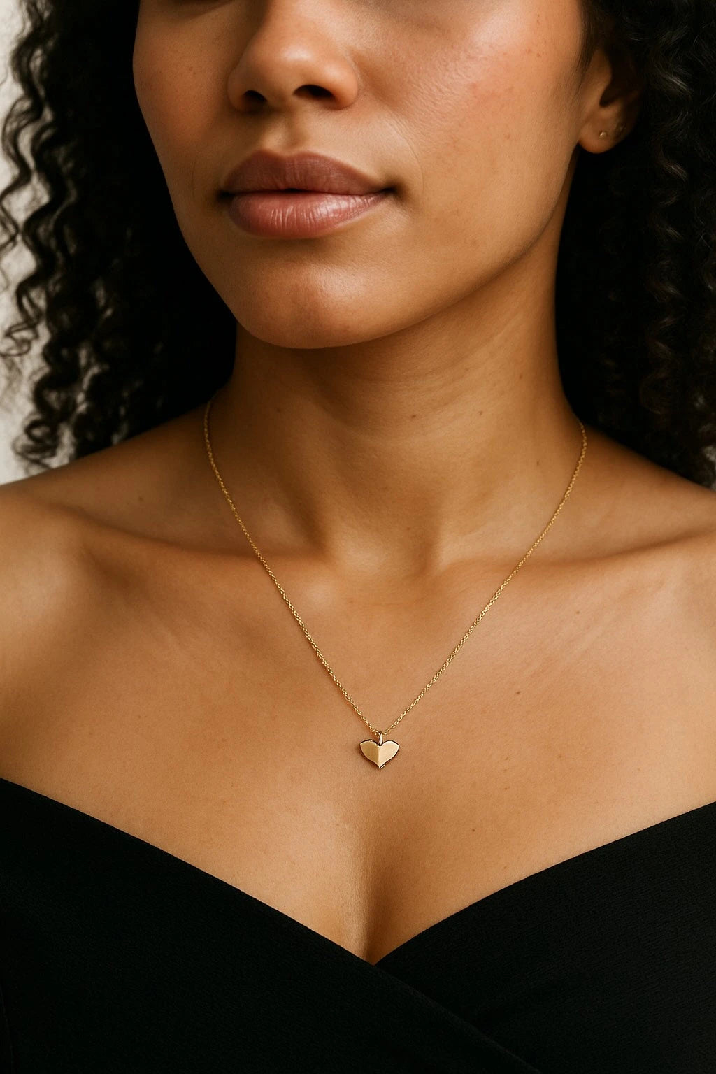 Close-up of a woman wearing a gold necklace with a heart pendant.