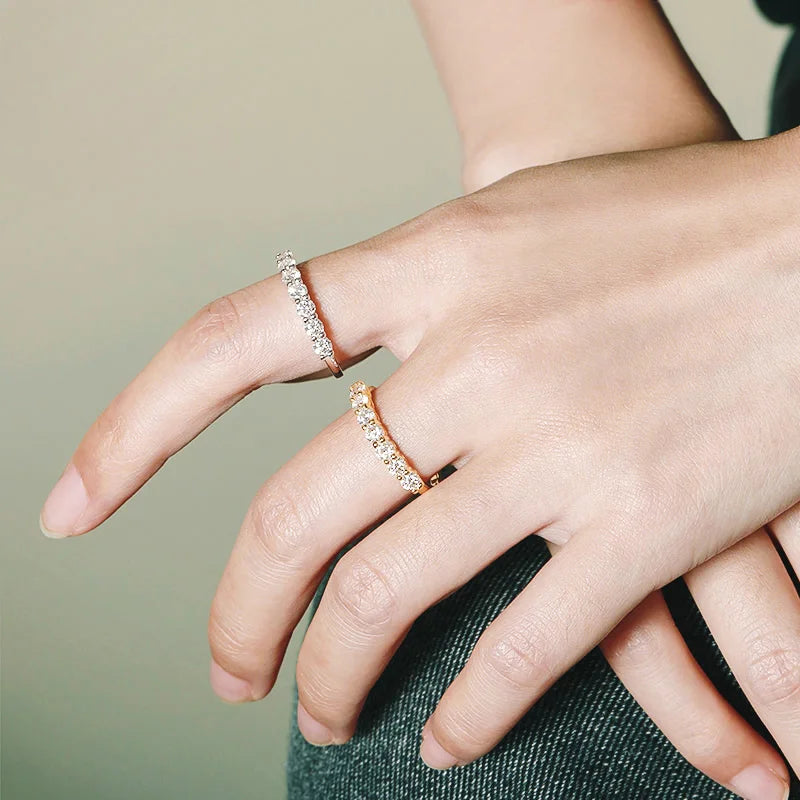 Close-up of a hand wearing two diamond rings on a neutral background