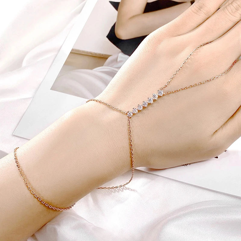 Rose gold bracelet with small diamonds on a wrist against a light background