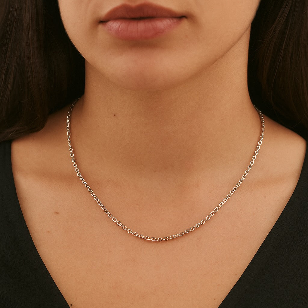 Close-up of a person wearing a silver chain necklace with a blurred background