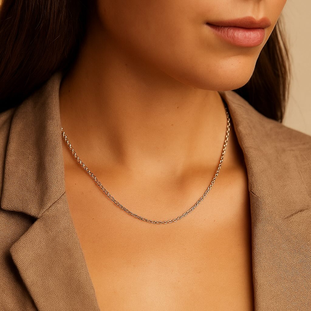 Close-up of a person wearing a silver necklace with a beige blazer.