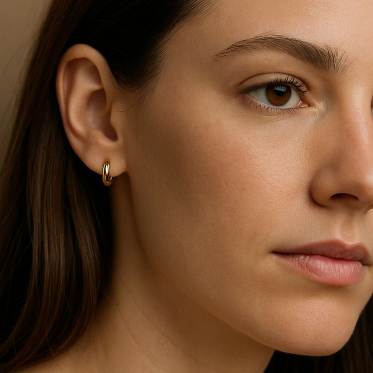 Close-up of a woman wearing a gold huggie hoop earring.