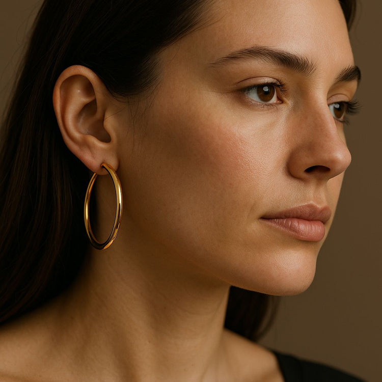 Close-up of a woman wearing a large gold hoop earring against a brown background