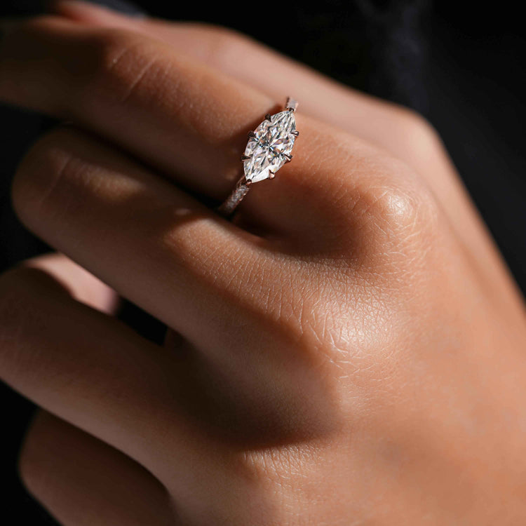 Close-up of a hand wearing a diamond ring with a dark background