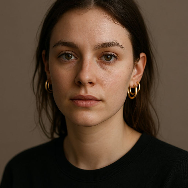 Woman wearing gold hoop earrings against a neutral background